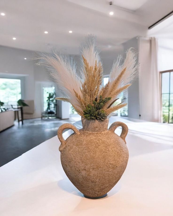 Large cement vase with handles amidst Pampas and succulents