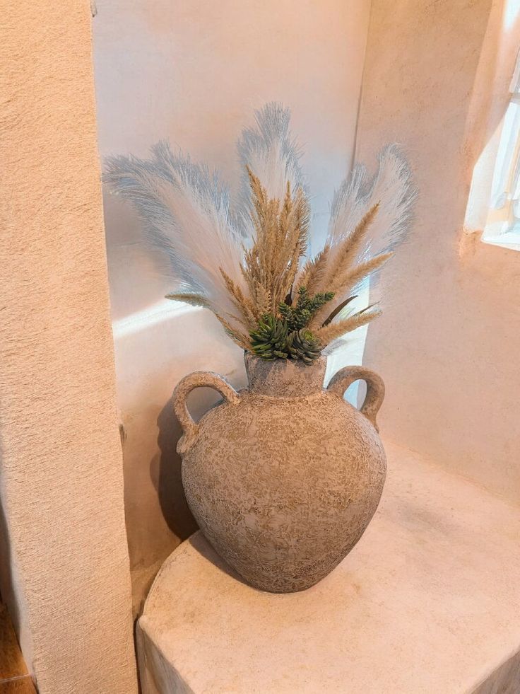 Large cement vase with handles amidst Pampas and succulents